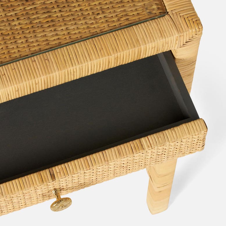 A close-up of the Made Goods Isla Desk shows its rattan frame, glass basket-weave top, and an open storage drawer that highlights the woven texture and round gold handle.