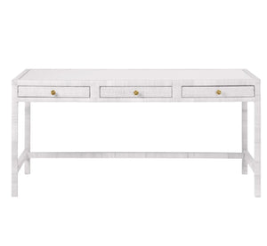 The Isla Desk by Made Goods is a rectangular white desk with three front drawers, each with a small round gold knob, and simple straight legs.