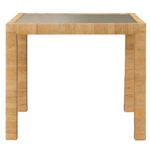 The Isla Game Table by Made Goods is a square rattan table with four straight legs, a natural rattan frame, and a glass top, shown against a white background.