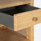 A close-up of the Made Goods Isla Nightstand Collection shows an open drawer with a round brass knob and a basket weave pattern on the rattan frame and lower shelf.