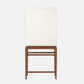 The Jamison Cabinet by Made Goods, a white rectangular panel with a simple modern design, stands vertically on walnut legs atop a wooden table against a plain background.