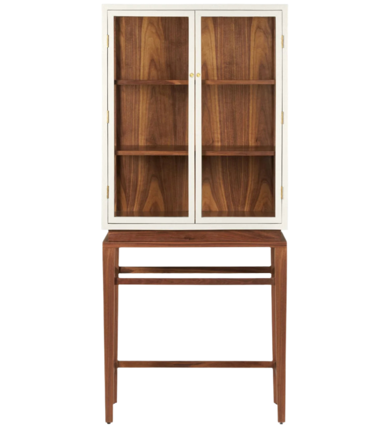 The Made Goods Jamison Cabinet features glass-paneled doors, three shelves, and stands on a matching wooden base with walnut legs and an open lower section.
