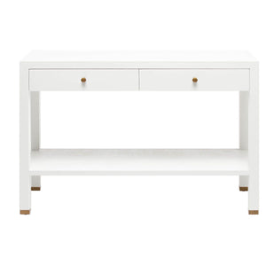 The Jarin Console Collection by Made Goods features a white wooden desk with a simple silhouette, two drawers with brass-hued knobs, textured finish, open lower shelf, and brass-accented feet, shown against a white background.