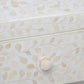 Close-up of a white Made Goods Lexi Dresser drawer, showcasing a decorative Indian pattern inlaid with camel bone and finished with a hexagonal knob.