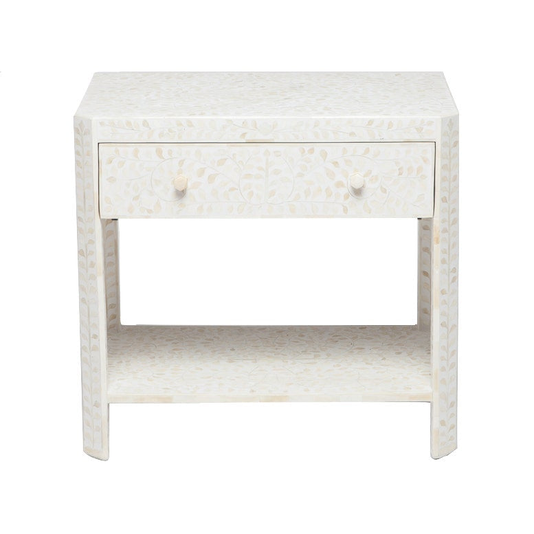 The Lexi Nightstand by Made Goods is a white, rectangular piece featuring a single drawer with two round knobs, a lower shelf, and a subtle leaf bone inlay design.
