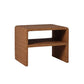 The Lynette Side Table in Dark Rattan by Made Goods showcases a rectangular wicker design with a woven facade and lower shelf, featuring a richly textured dark brown finish. Set against a plain white background, this side table combines classic aesthetics with functional storage, making it an ideal addition to any space.