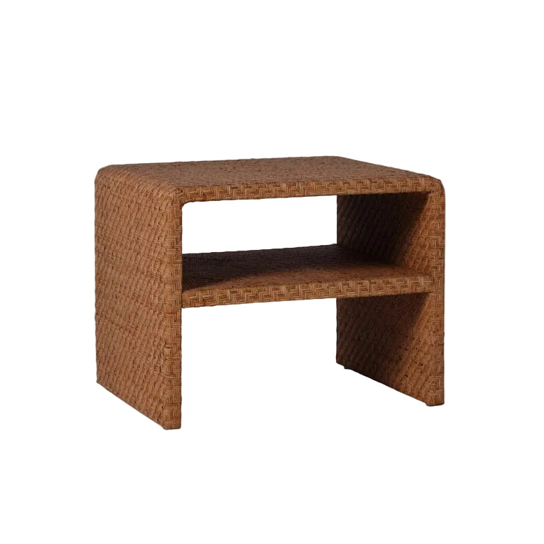 The Lynette Side Table in Dark Rattan by Made Goods showcases a rectangular wicker design with a woven facade and lower shelf, featuring a richly textured dark brown finish. Set against a plain white background, this side table combines classic aesthetics with functional storage, making it an ideal addition to any space.