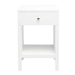 The Maris Nightstand Collection by Made Goods features a white wooden nightstand with raised feet, one drawer with a round knob and overlay panels, plus an open lower shelf, shown against a plain white background.