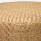 A close-up view of the Moselle Coffee Table by Made Goods, featuring a round woven rattan surface with a herringbone pattern.