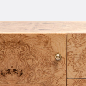 Close-up of the Xander Buffet by Made Goods, featuring a burled wood finish with natural grain patterns and a single faceted brass knob on the front.