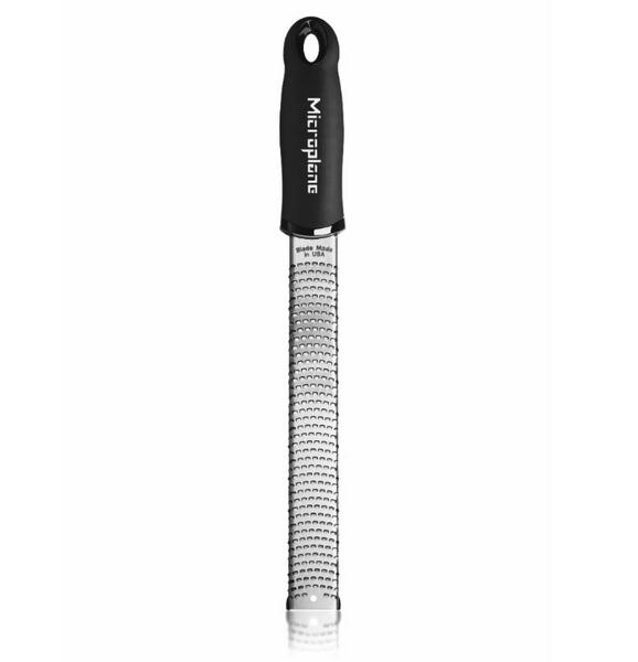 The Microplane Premium Classic Zester in black, manufactured by Microplane, features a narrow, surgical-grade stainless steel grating surface that ensures precision and durability. Its ergonomic handle provides a comfortable grip for effortless zesting.