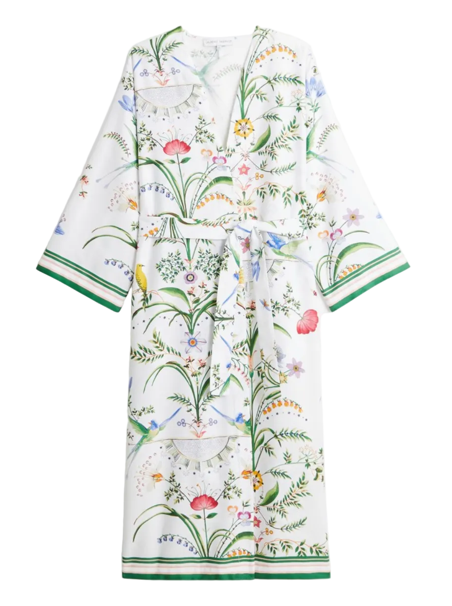 Yves Delorme x Laurence Tavernier Botanic Dressing Gown in white cotton sateen with a colorful botanical floral print, waist tie, and green striped trim on the sleeves and hem.