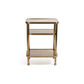 The Aman Etagere by Zodax is a small, rectangular gold metal side table with three tiers and rounded edges. Its minimalist design stands out elegantly against a plain white background.
