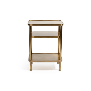 The Aman Etagere by Zodax is a small, rectangular gold metal side table with three tiers and rounded edges. Its minimalist design stands out elegantly against a plain white background.