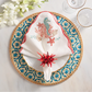 The Kim Seybert Marina Napkin Set adds ocean-inspired elegance to your table, especially when paired with woven placemats, blue and gold plates, coral napkin rings, and chic glassware.