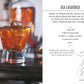 Two glasses of Old Fashioned cocktails with ice and orange garnish sit on a tray next to “Gatsby Cocktails” by Simon & Schuster, which features the drink’s recipe and history, celebrating its legacy among classic cocktail recipes and iconic 1920s cocktails.