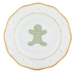 This Herend Christmas Gingerbread Man Dessert Plate features a gold-rimmed gingerbread man design, accented with green trees and yellow buttons.