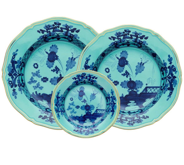 The GINORI 1735 Oriente Italiano Iris with Gold Collection by Ginori 1735 includes a set of three turquoise porcelain pieces featuring intricate dark blue floral patterns and gold-edged rims, exuding an exotic beauty. The set consists of two large plates and one smaller bowl.