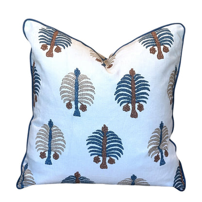 Introducing the Gobi Blue Down Pillow by Hive Custom Pillows—a 22x22 white square throw pillow adorned with blue, brown, and beige tree-inspired embroidered patterns and finished with elegant blue piping along the edges. Expertly handmade, this pillow can be custom crafted with a luxurious down fill for enhanced comfort and style.