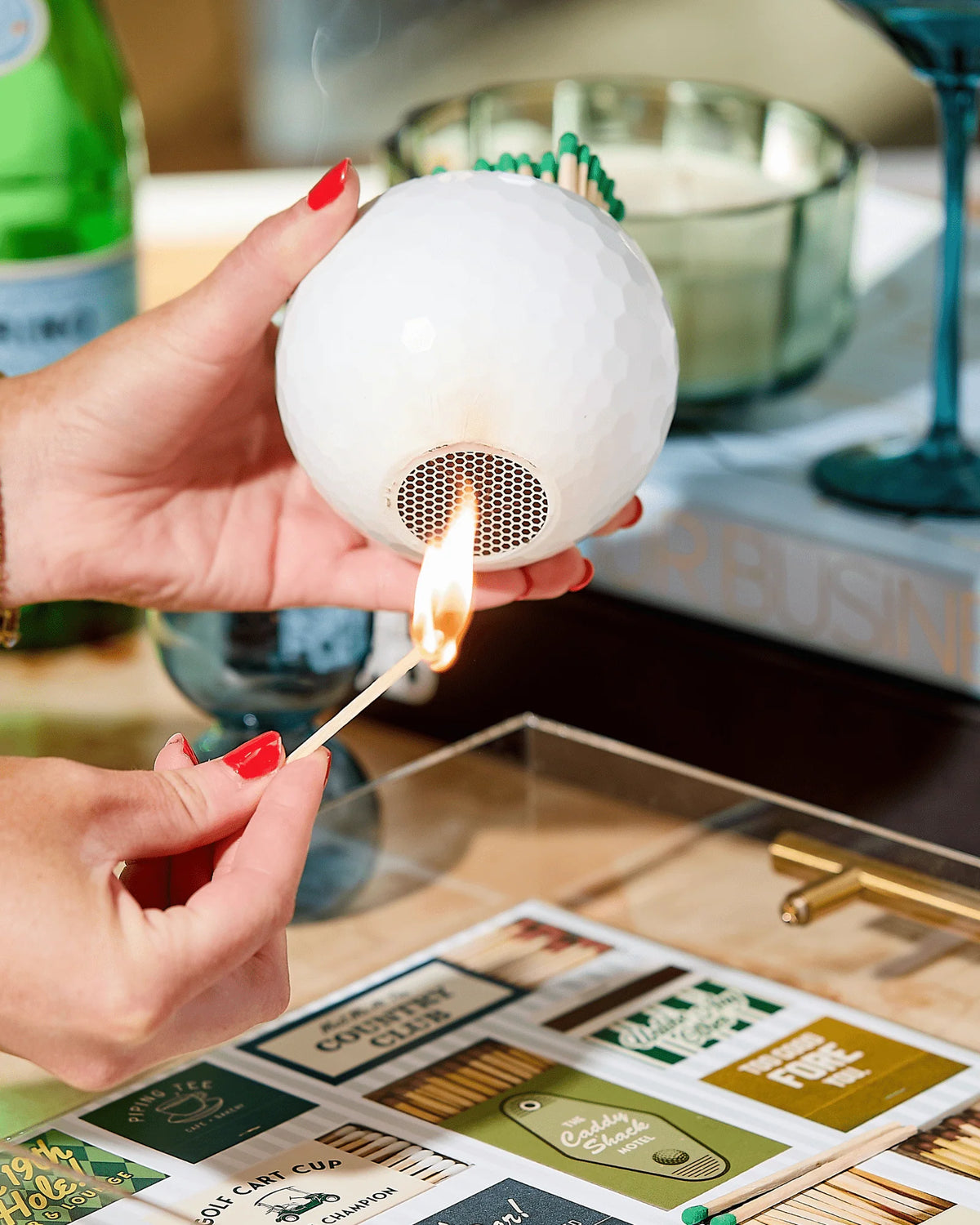 A person lights a match against the textured surface of a Golf Match Striker.