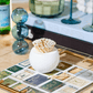 The Golf Match Striker Collection by Tart by Taylor features a white textured round container that adds chic style to your coffee table, neatly holding matches and serving as a sleek match strike among books and decor.