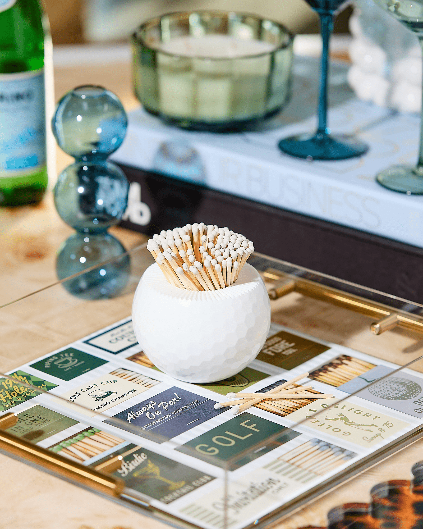 The Golf Match Striker Collection by Tart by Taylor features a white textured round container that adds chic style to your coffee table, neatly holding matches and serving as a sleek match strike among books and decor.