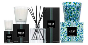 The Nest Forest Rain Scent Collection features a scented candle, reed diffuser, and decorative candle in black and patterned green-blue packaging, evoking an aquatic veil of fig leaves.