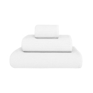 Three white towels of varying sizes from the Puro White Bath Collection by GRACCIOZA, featuring Zero Twist technology for natural comfort and high absorbency, neatly stacked against a plain white background.