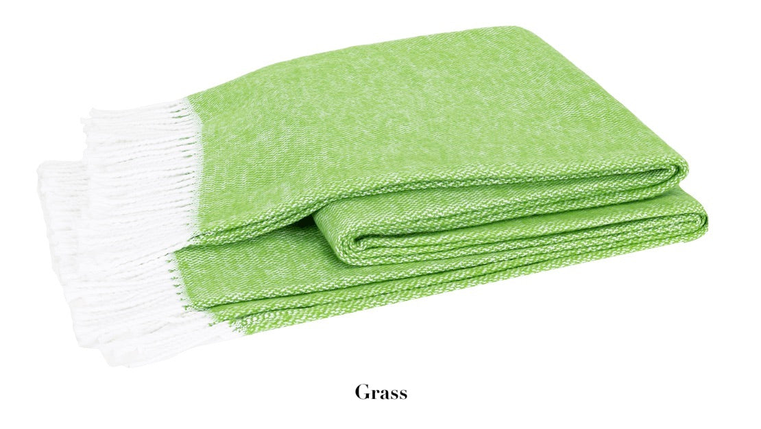 The Pezzo Throw Collection by Matouk features a folded light green brushed cotton blanket with white fringes on one end. Cozy and inviting, it's perfect for adding warmth and style to any space.