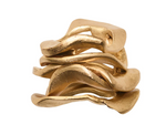 The Kim Seybert Gold Flux Napkin Ring features multiple intertwined, wavy bands in a sculptural gold design, creating an organic and modern look against a white background—an elegant accent that adds sophisticated flair to any table setting.