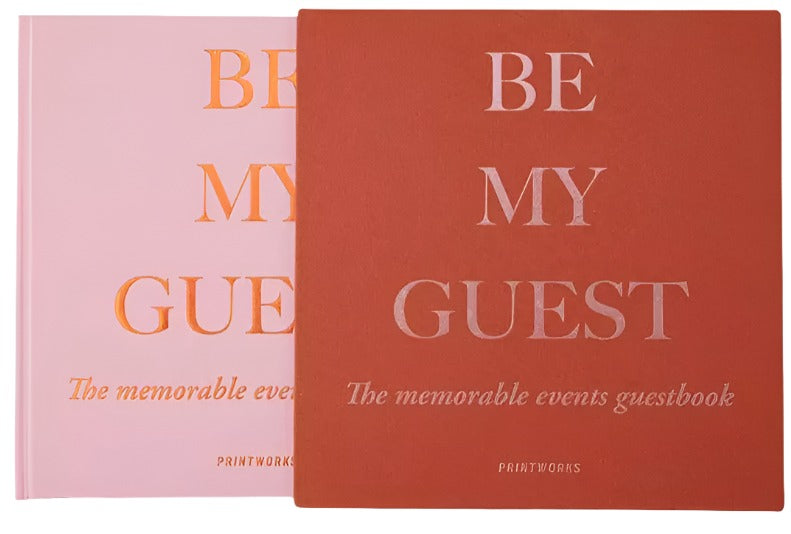 Two "Be My Guest Book" guest books by PrintWorks in rust and pink are shown—ideal for capturing memories and bringing stylish flair to your home.
