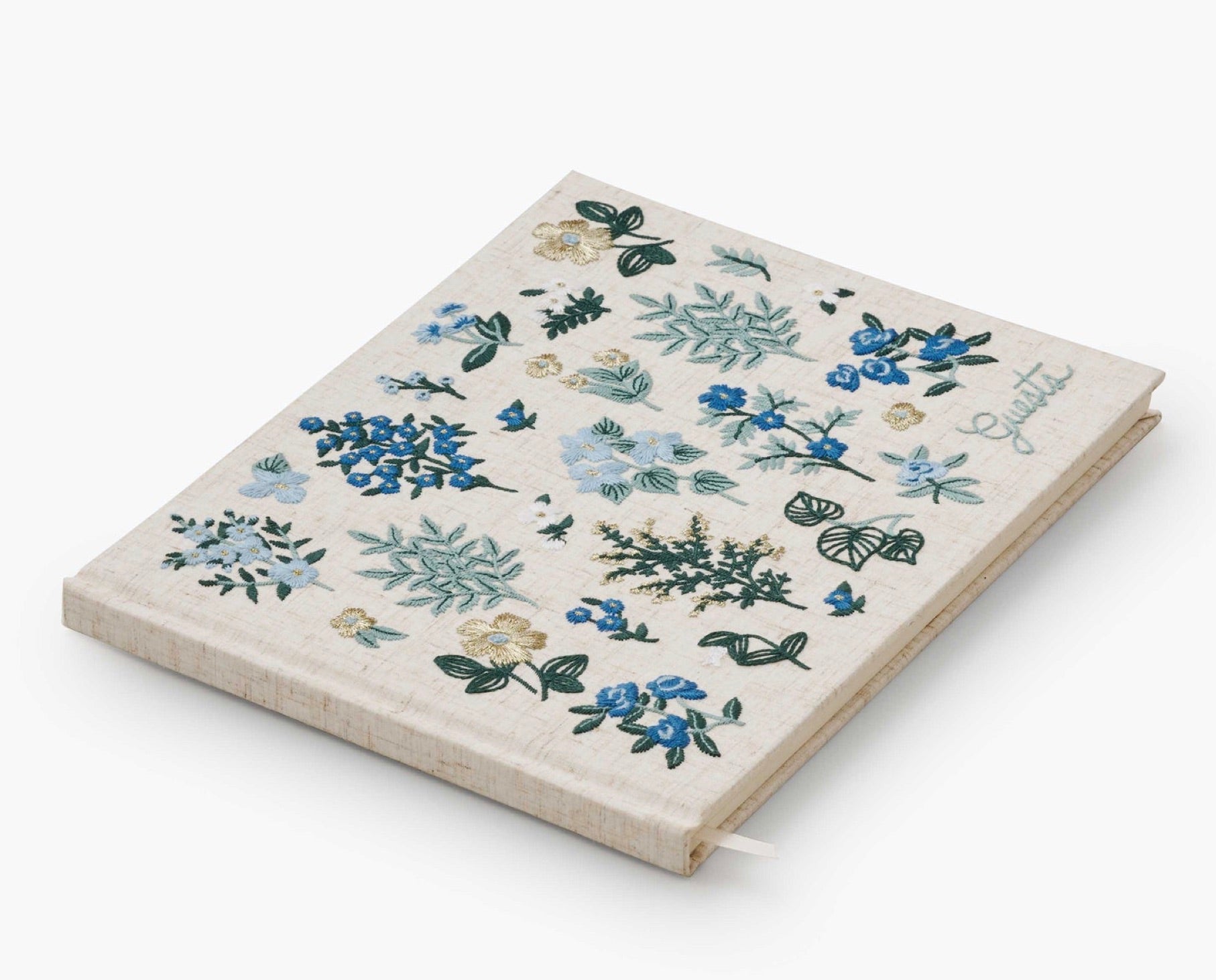 The Riffle Paper Co. Wildwood Embroidered Guest Book is a closed fabric-covered journal featuring blue and green floral embroidery and "Gratitude" stitched on the cover.