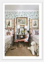 A woman sits on a bench between two twin beds in a Nick Mele Photography location, reading a book, surrounded by plush toys and Nick Mele Fine Art I Love Capitalism.
