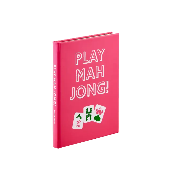 A stylish pink book titled “Play Mahjong!” by Graphic Image, featuring bold white text and two illustrated mahjong tiles on the cover, stands upright against a white background. Ideal for anyone interested in learning how to play mahjong or exploring American Mahjong strategies, this eye-catching guide is both informative and visually appealing.