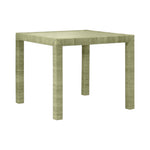 The Isla Game Table in Sage by Made Goods is a square, light green table with four straight legs and a textured surface inspired by rattan, shown against a plain white background.