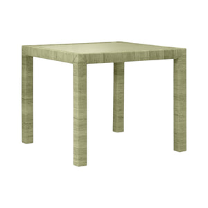 The Isla Game Table in Sage by Made Goods is a square, light green table with four straight legs and a textured surface inspired by rattan, shown against a plain white background.
