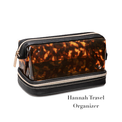 The Stephanie Johnson Miami Tortoise Travel Collection organizer features a tortoiseshell pattern with a black base, double zippers with gold pulls, and faux-leather trim. “Hannah Travel Organizer” is printed on the front.