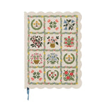 The Helena Softcover Journal by Rifle Paper Co. is a cream-colored journal with scalloped edges and a linen textured cover, featuring a floral pattern of 15 blocks—each showcasing different flower arrangements—and comes complete with a blue ribbon bookmark.