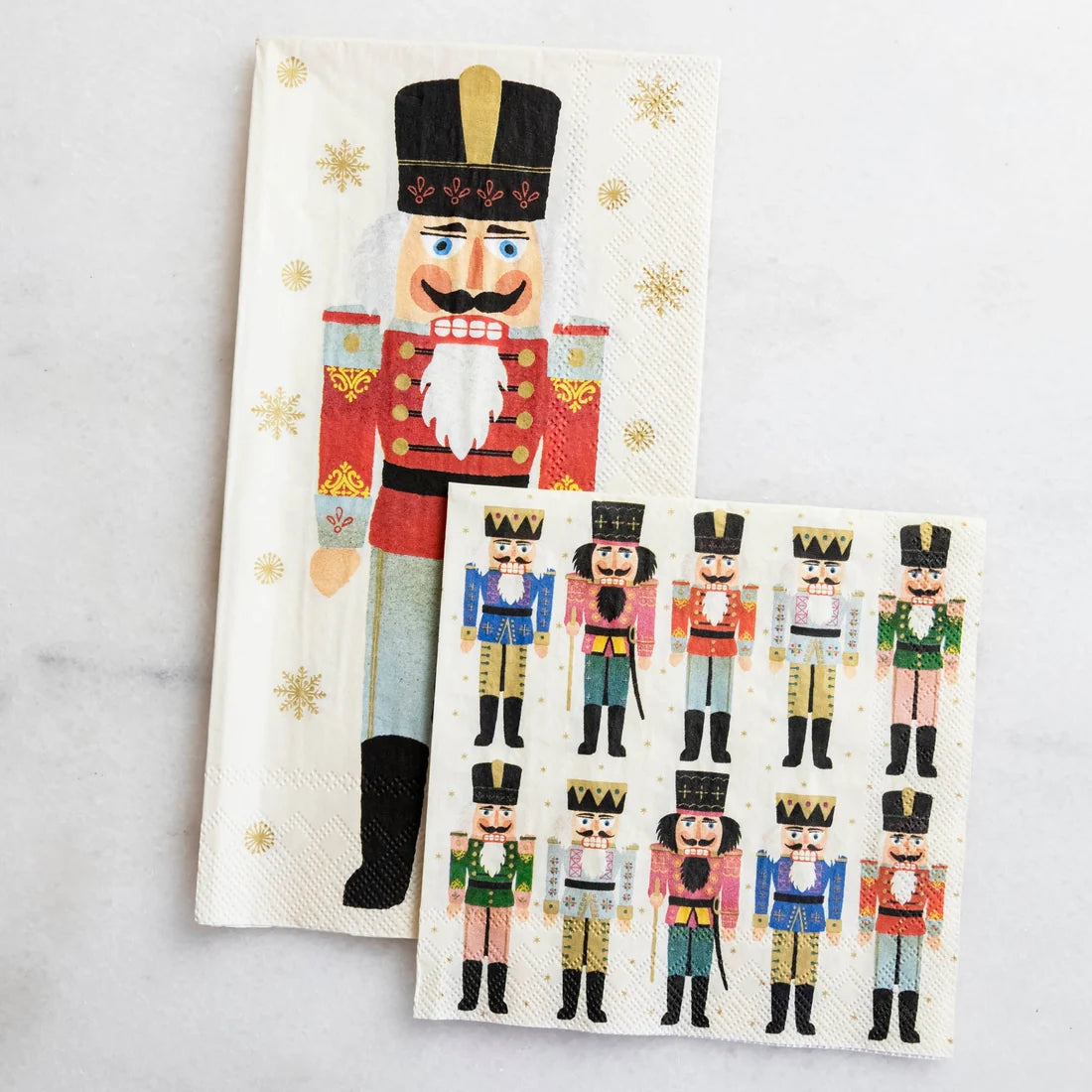 A long Nutcracker Collection napkin and a square napkin featuring ten smaller nutcrackers, both with gold stars, perfect for your holiday table decor.