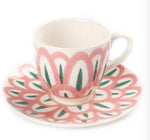 A white porcelain cup and saucer from Themis Z's Symi Green and Pink Dinnerware Collection, featuring a floral pattern.