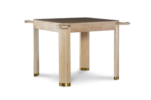 The Willie Oak Game Table by Highland House features a square oak design with four thick legs, gold-colored caps, and horizontal corner protrusions, shown against a white background.