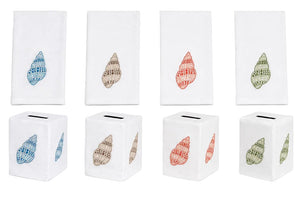 Four embroidered linen napkins and four matching tissue box covers from the Haute Home Speckled Conch Coaster & Bath Collection—each featuring a unique seashell motif in blue, brown, red, and green—are arranged in two rows on a white background.