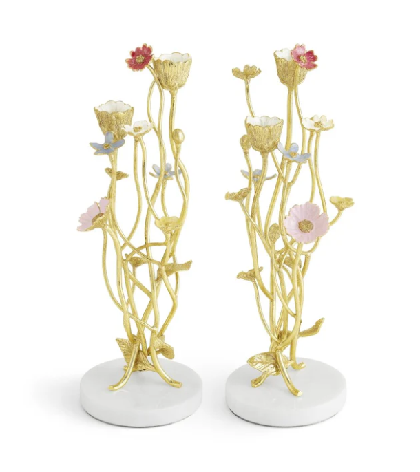 The Michael Aram Wildflowers Candleholders feature gold-colored metal with sculpted floral accents, pink and blue flowers, and white round bases.