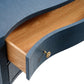 A close-up of the Londyn Buffet by Made Goods showcases its blue curved wood, single partially open drawer with a round metal knob, light wood interior, and natural grasscloth accents for timeless style.