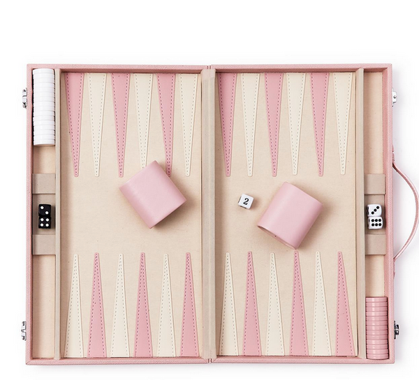 The Two's Company Terra Pink Backgammon Game Set features pink and beige vegan leather with an open case displaying checkers, dice, and dice cups.