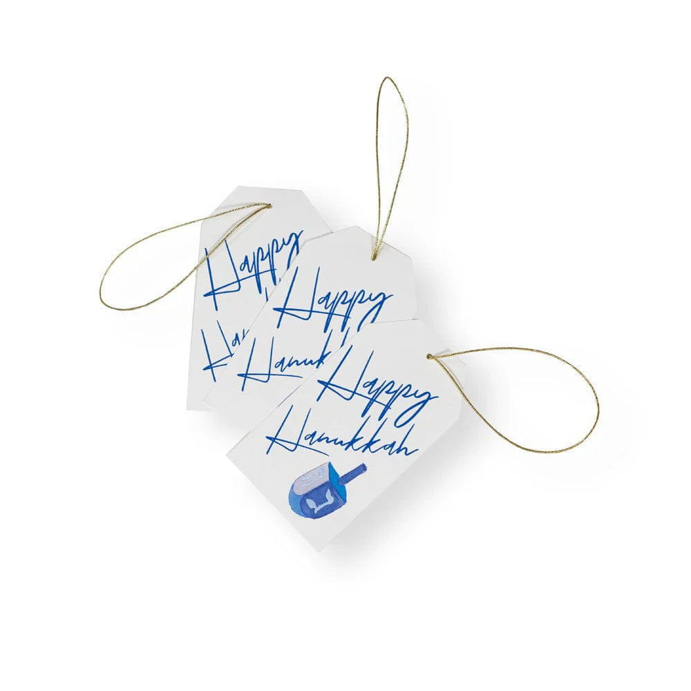 The Caspari Happy Hanukkah Foil Hanging Gift Tag set includes three white tags made of quality cardstock, each with "Happy Hanukkah" in blue script and a dreidel design—perfect festive ornaments for your holiday gifts.