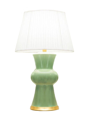The Ginger Table Lamp by Hwang Bishop features a green ceramic sculptural base, a wide pleated white shade, and an elegant gold base, displayed against a white background.