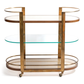 The Zodax Sloane Bar Cart features a brass frame, mesh top and bottom shelves, a glass middle shelf, and four wheels—ideal for showcasing cocktail accessories in your home bar.