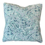 The Cowrie Shell Aqua Outdoor Pillow by Associated Design features an abstract leaf pattern in blue, white, and gray on a light blue background, crafted from premium materials for outstanding comfort.