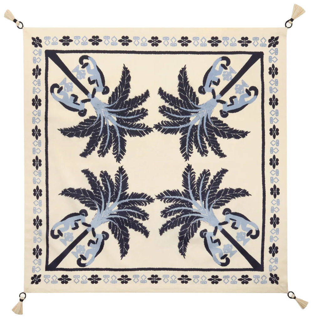 The Ikat Amazónico Napkins by Johanna Ortiz feature a cream background, blue and navy palm tree motifs, a decorative border, and tassels—perfect for adding tropical chic elegance to your table setting.